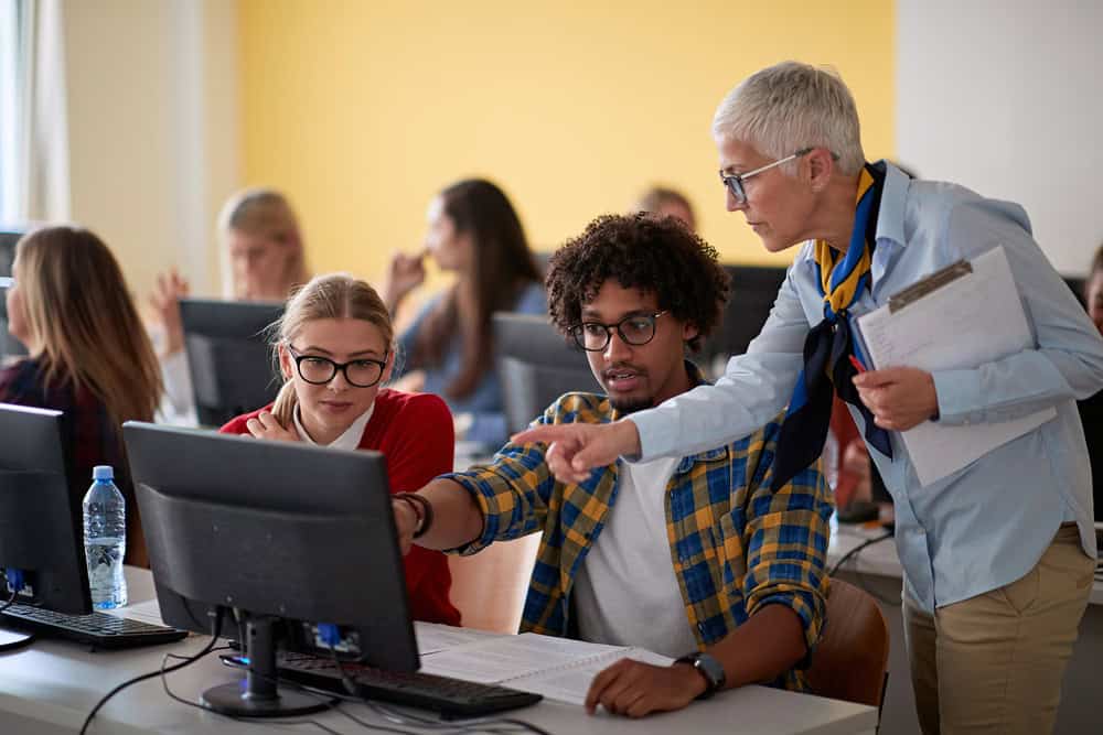 Female professor checking students work at an informatics lecture Female professor checking students work at an informatics lecture in the university computer classroom